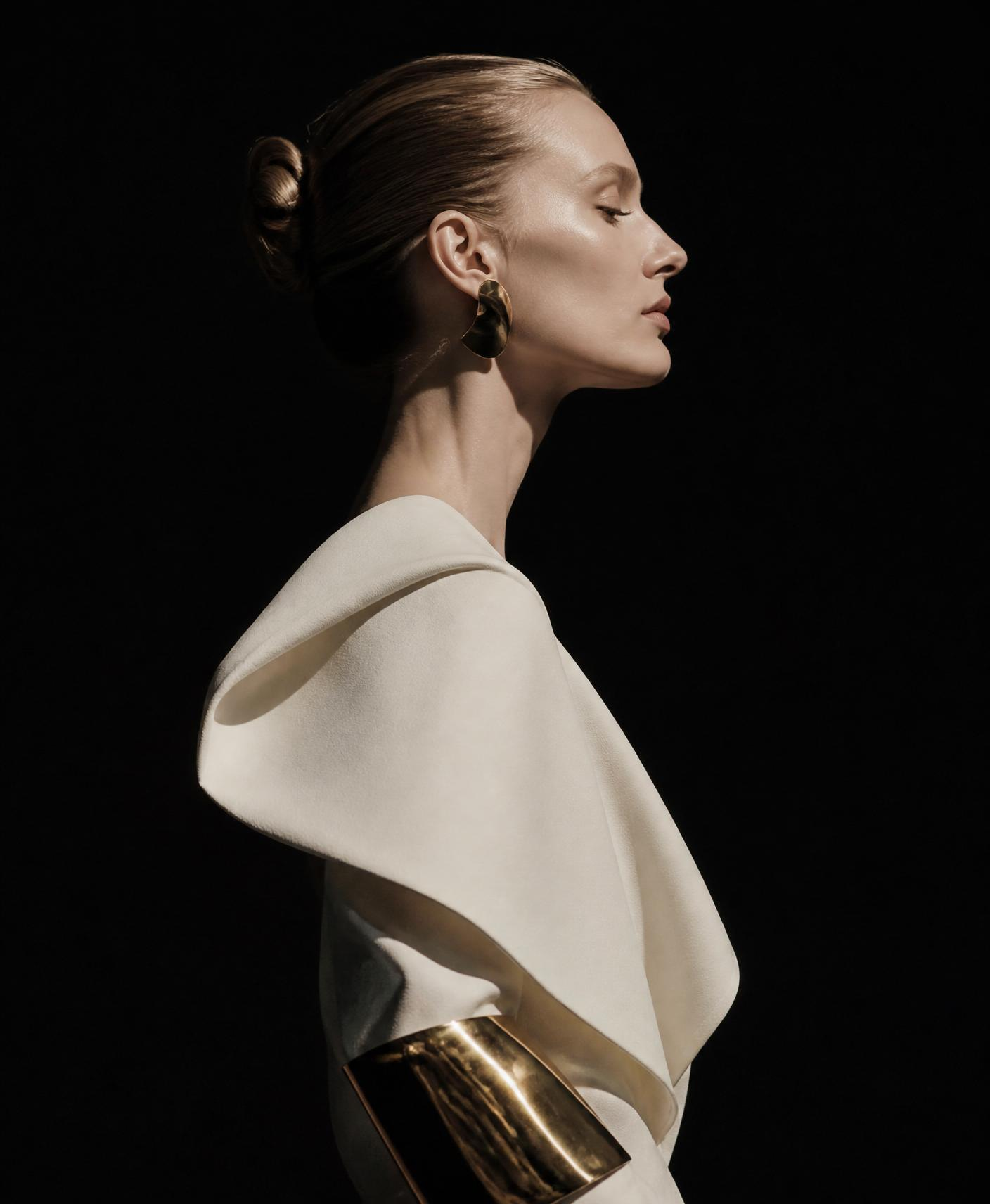 Editorial portrait of model in profile against deep shadow